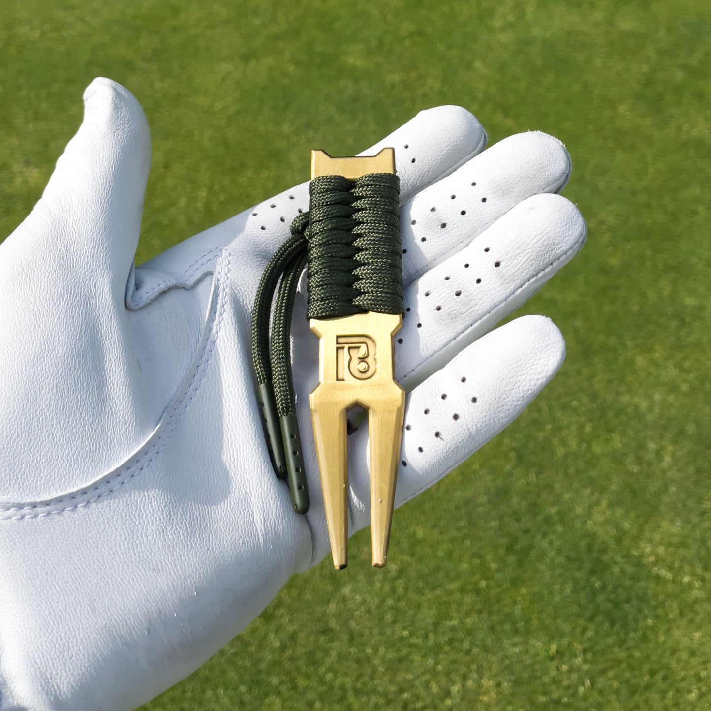 Golf Ballmarker und Divottool Gold in Geschenkbox von 18Undergolfclub auf einem Golfgrün. Putting Green Performance Set.